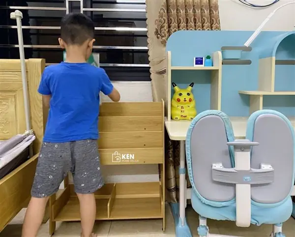 Bé tự chọn đồ trên kệ Montessori tại nhà, chụp từ sau lưng